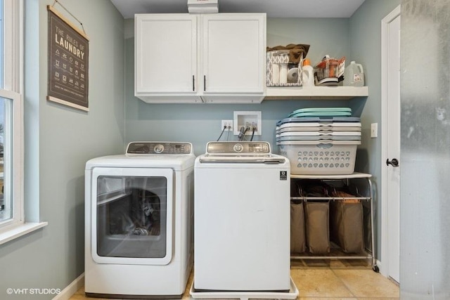 washroom with light tile patterned floors, washer and clothes dryer, and cabinets