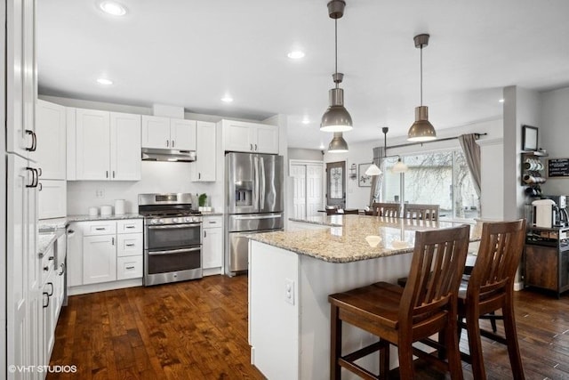 kitchen with white cabinetry, appliances with stainless steel finishes, a breakfast bar area, and pendant lighting