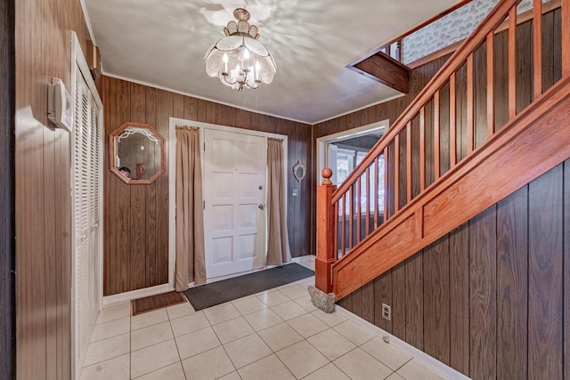 tiled foyer entrance featuring crown molding, a chandelier, and wooden walls