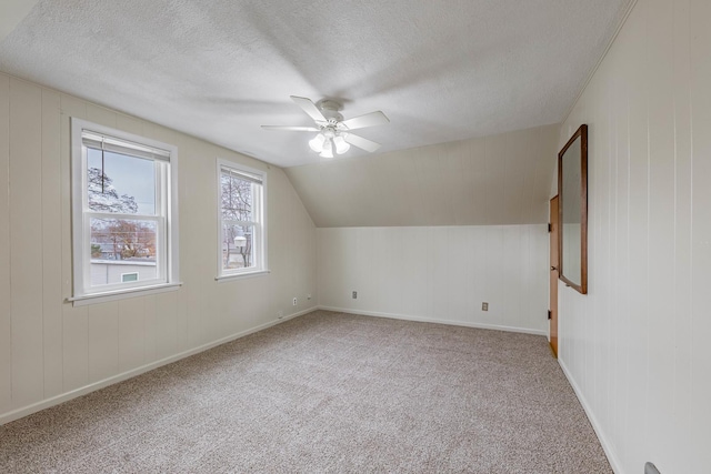 bonus room featuring lofted ceiling, a textured ceiling, ceiling fan, and carpet