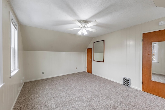 bonus room with ceiling fan, lofted ceiling, carpet floors, and a textured ceiling