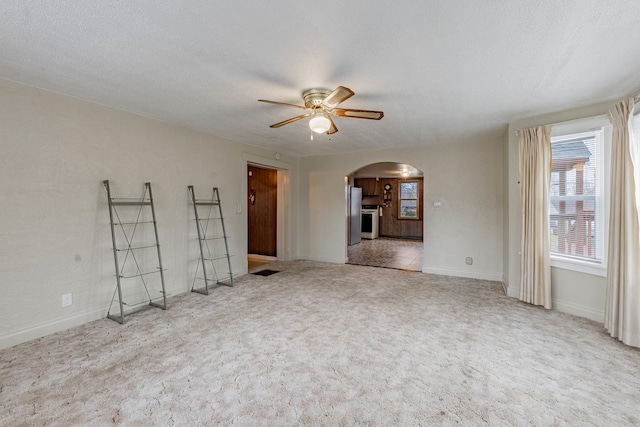 unfurnished living room featuring light carpet, a textured ceiling, and ceiling fan