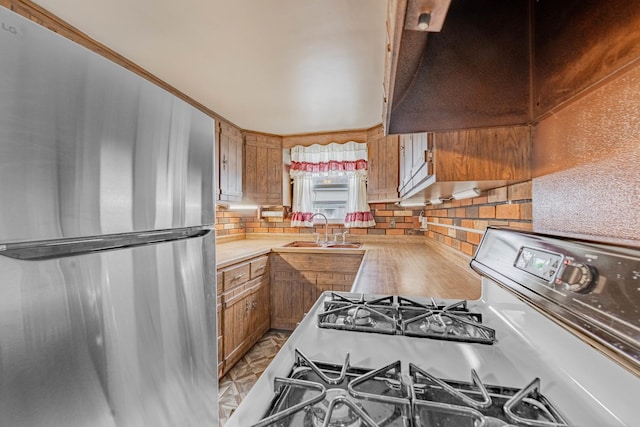 kitchen featuring sink, range with gas cooktop, and stainless steel refrigerator