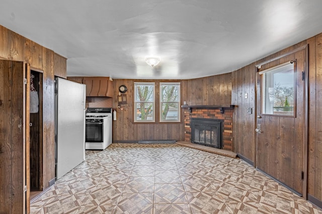 kitchen featuring stainless steel refrigerator, light parquet flooring, wooden walls, and white gas range oven