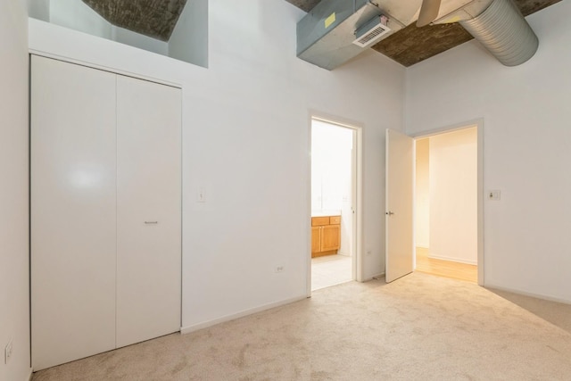 unfurnished bedroom with a towering ceiling and light colored carpet