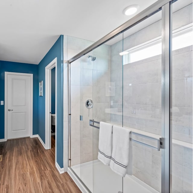 bathroom with hardwood / wood-style flooring, toilet, and a shower with shower door