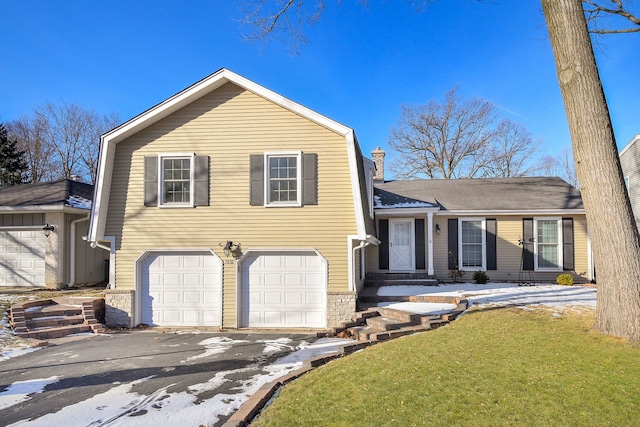 split level home featuring an attached garage, a chimney, a front lawn, and aphalt driveway