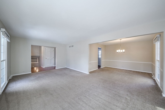 empty room featuring an inviting chandelier, baseboards, visible vents, and dark carpet