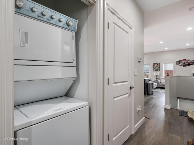 laundry area featuring stacked washer / drying machine and dark hardwood / wood-style floors