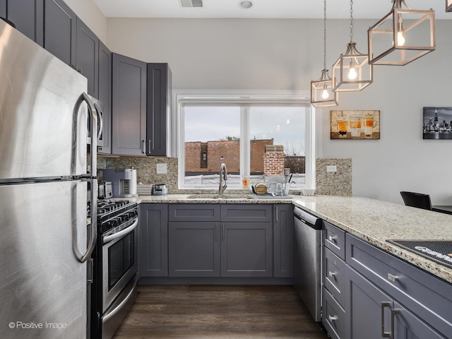 kitchen featuring stainless steel appliances, light stone countertops, gray cabinets, and backsplash