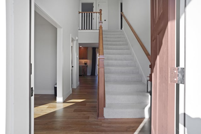 stairs with a towering ceiling and wood-type flooring