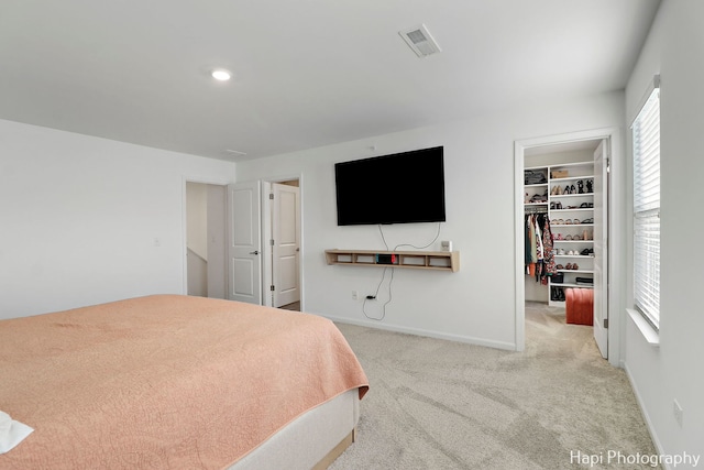 carpeted bedroom featuring a spacious closet and a closet