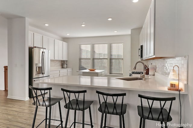 kitchen with sink, stainless steel appliances, kitchen peninsula, and white cabinets