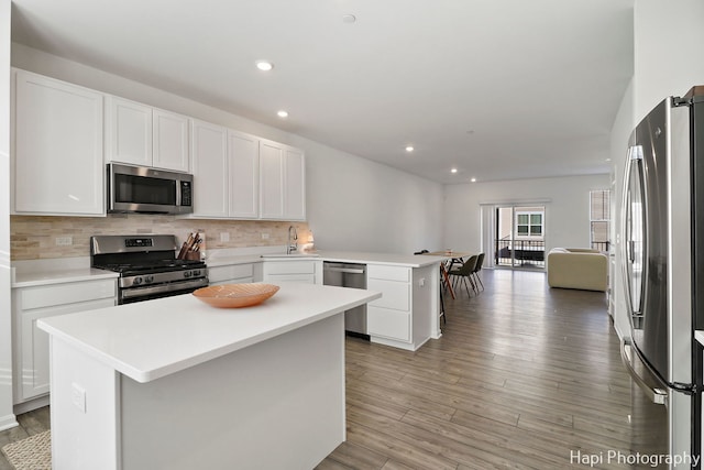 kitchen with stainless steel appliances, a center island, sink, and white cabinets