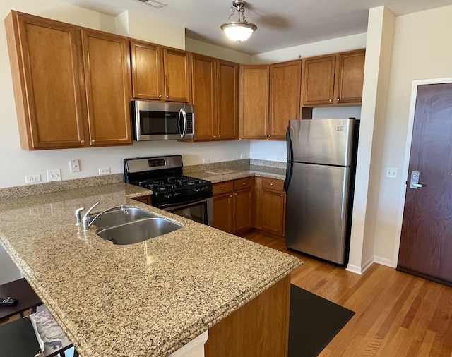 kitchen featuring light hardwood / wood-style floors, stainless steel appliances, kitchen peninsula, and sink