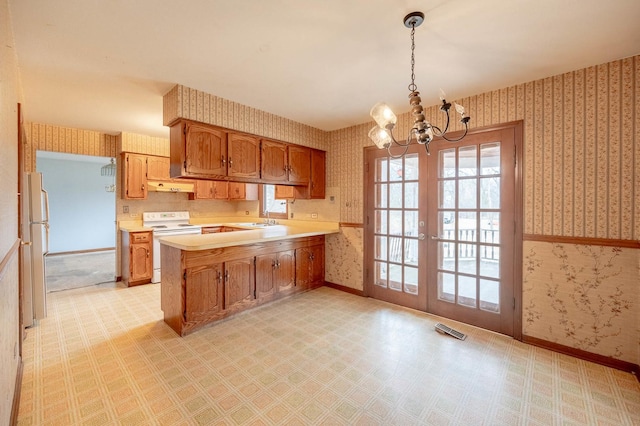 kitchen with sink, white appliances, hanging light fixtures, french doors, and kitchen peninsula