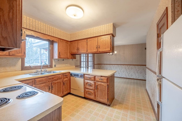 kitchen with white appliances, kitchen peninsula, and sink