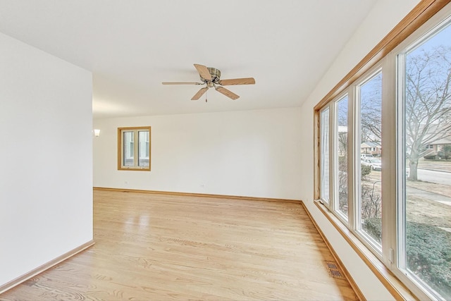 empty room featuring ceiling fan, a wealth of natural light, and light wood-type flooring