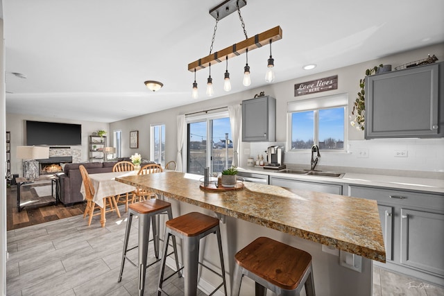 kitchen featuring gray cabinets, sink, a wealth of natural light, and a kitchen breakfast bar