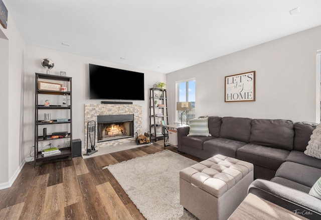 living room featuring dark hardwood / wood-style floors and a stone fireplace