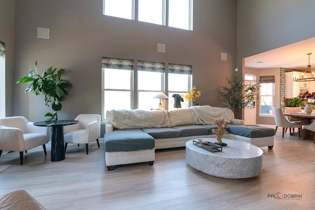 living room featuring a high ceiling, a chandelier, and light wood-type flooring