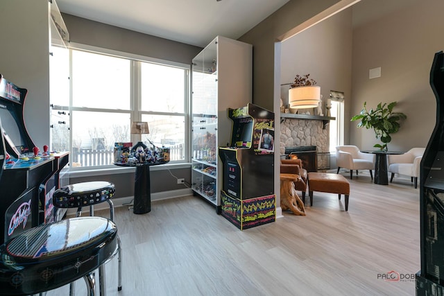 playroom with a stone fireplace and light wood-type flooring