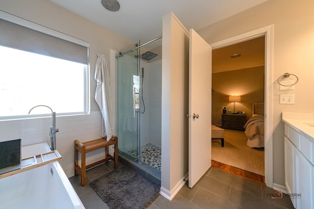 bathroom featuring tile patterned flooring, vanity, independent shower and bath, and tile walls