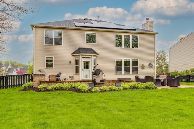 back of property featuring an outdoor living space, a yard, and solar panels