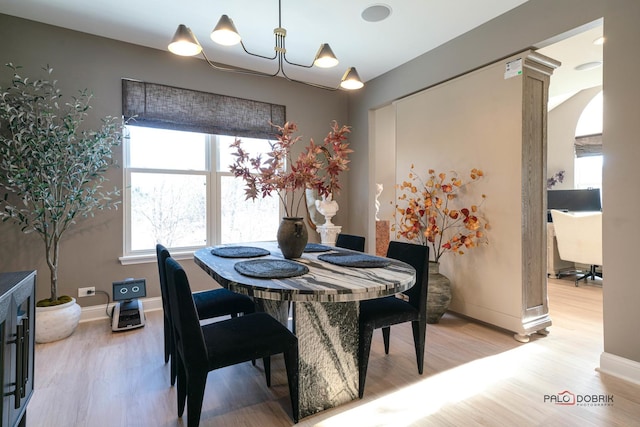 dining area featuring hardwood / wood-style flooring, an inviting chandelier, and ornate columns