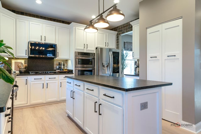 kitchen with white cabinetry, decorative light fixtures, stainless steel appliances, and a kitchen island