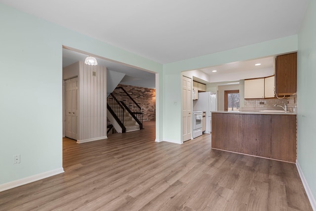 kitchen with tasteful backsplash, white appliances, light hardwood / wood-style floors, and kitchen peninsula