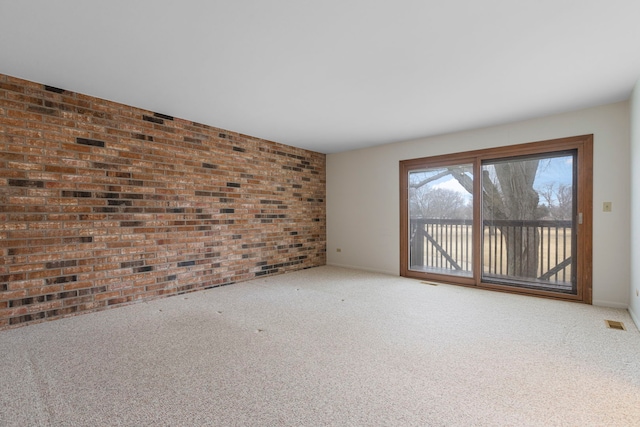 carpeted spare room with brick wall