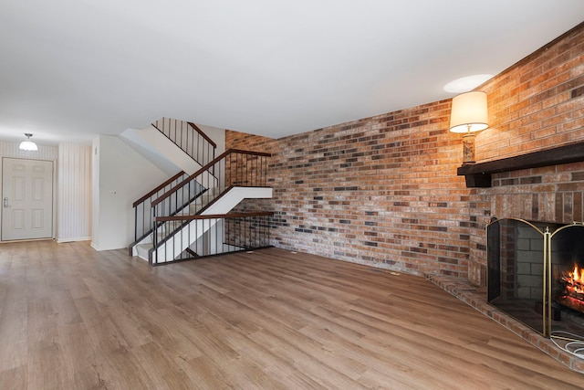 unfurnished living room with brick wall, a fireplace, and light hardwood / wood-style floors