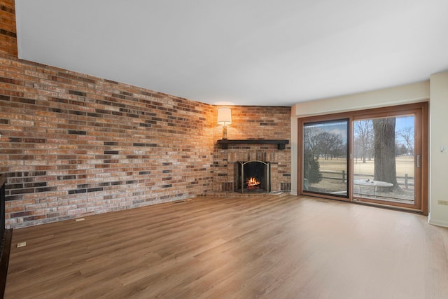 unfurnished living room with brick wall, wood-type flooring, and a fireplace