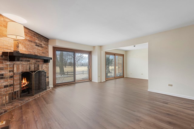 unfurnished living room featuring a brick fireplace and dark hardwood / wood-style floors