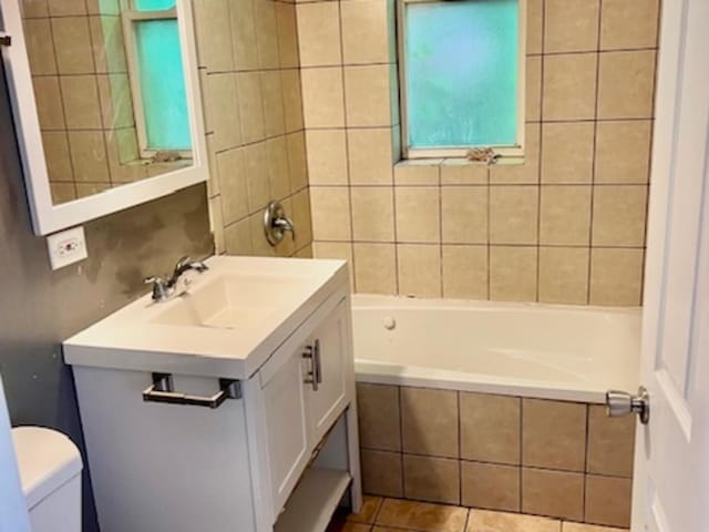 full bathroom featuring tile patterned flooring, vanity, tiled shower / bath, and toilet