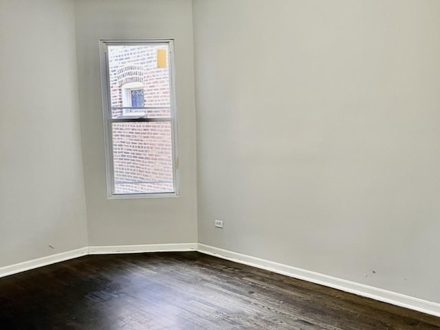 spare room featuring dark wood-type flooring and plenty of natural light