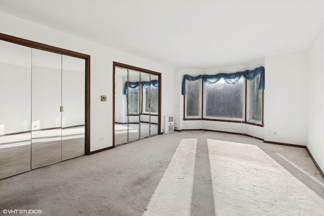 unfurnished bedroom featuring light carpet, two closets, and multiple windows