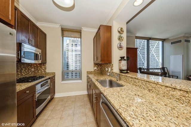 kitchen with sink, appliances with stainless steel finishes, backsplash, light stone countertops, and ornamental molding