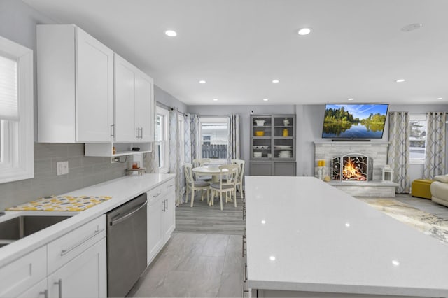 kitchen featuring white cabinetry, a center island, dishwasher, and decorative backsplash