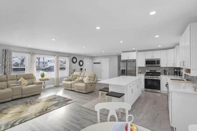 kitchen featuring sink, a breakfast bar area, white cabinetry, appliances with stainless steel finishes, and a kitchen island