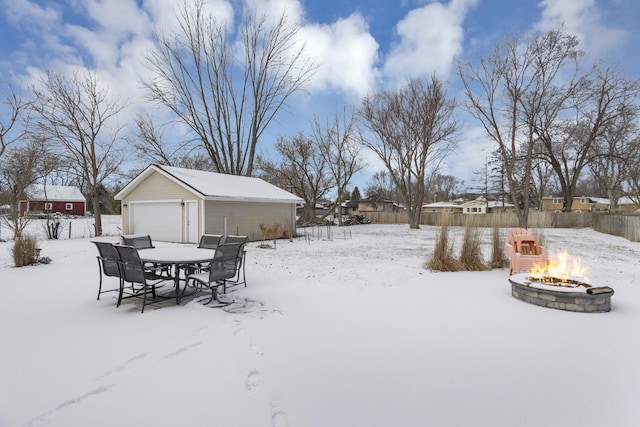 yard covered in snow with an outbuilding, a garage, and a fire pit