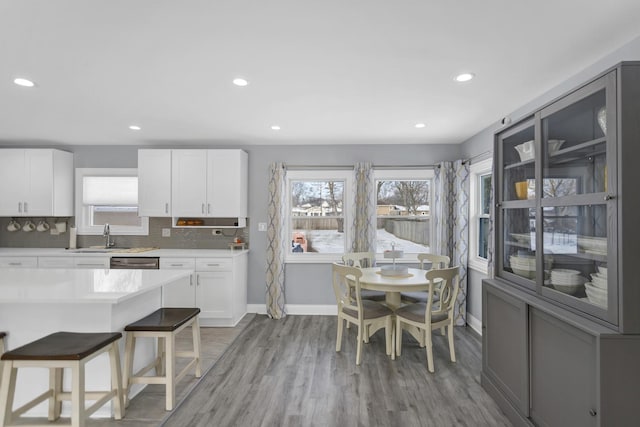 kitchen with tasteful backsplash, white cabinetry, a healthy amount of sunlight, and light wood-type flooring