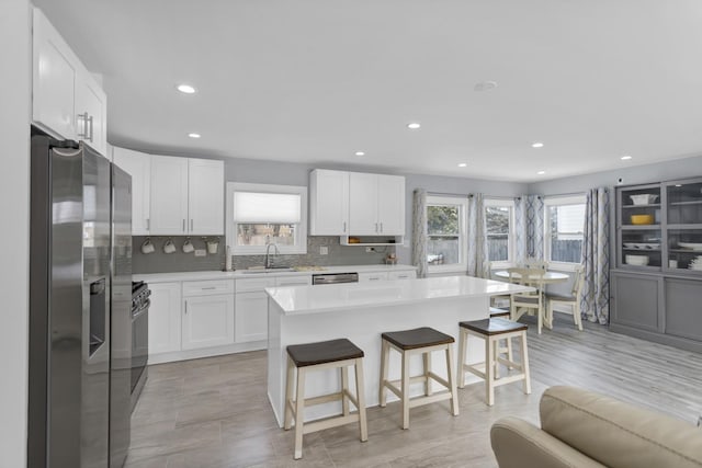 kitchen featuring sink, a center island, appliances with stainless steel finishes, a kitchen breakfast bar, and white cabinets