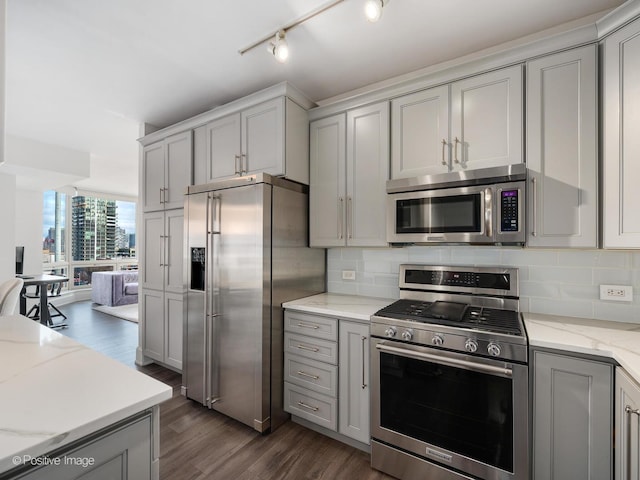 kitchen with light stone counters, backsplash, gray cabinets, and stainless steel appliances