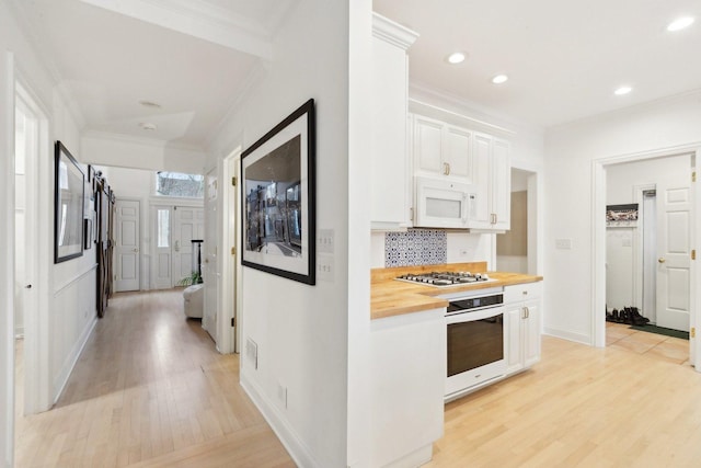 kitchen featuring wood counters, white cabinets, white appliances, crown molding, and light wood-type flooring