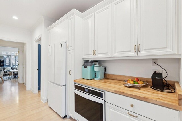 kitchen featuring wood counters, sink, white cabinetry, decorative light fixtures, and dishwasher