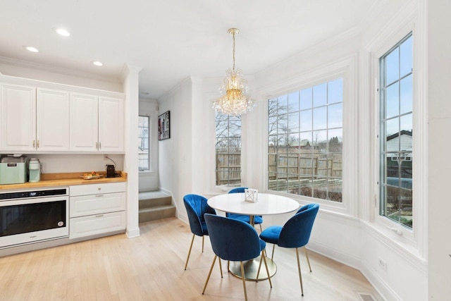 dining space featuring crown molding, a chandelier, and light wood-type flooring