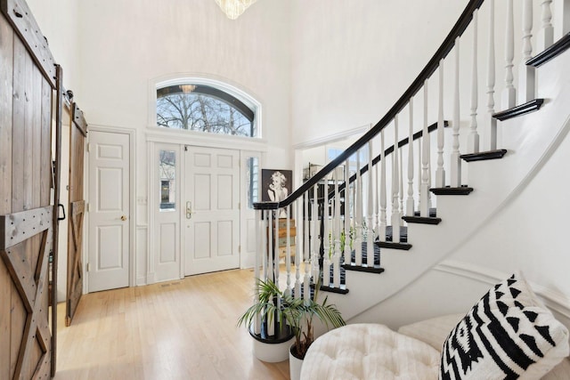 entryway with a barn door, a towering ceiling, and light hardwood / wood-style flooring