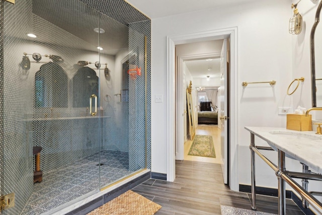 bathroom featuring hardwood / wood-style flooring, a shower with shower door, and sink